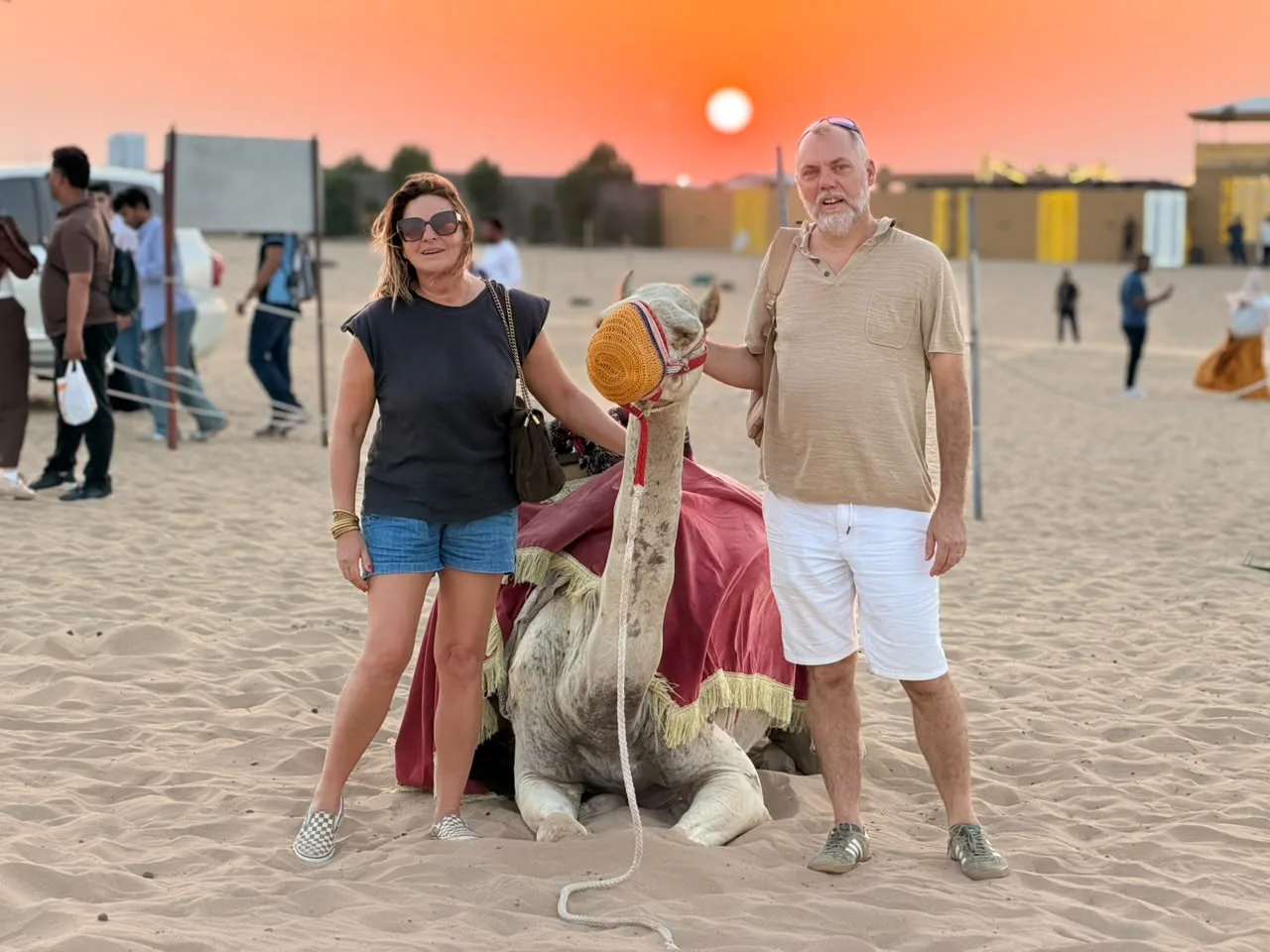 Guests with a camel at sunset during a VIP Abu Dhabi desert safari