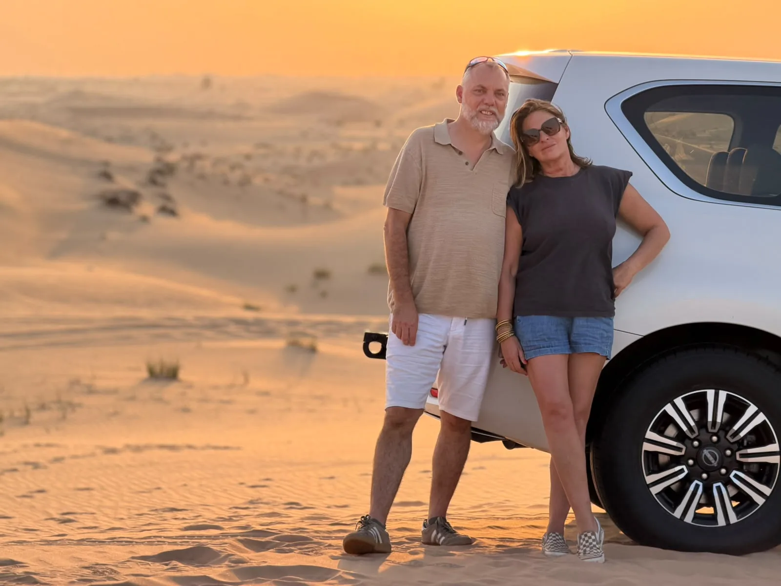 Couple enjoying sunset in the Abu Dhabi desert beside a 4x4