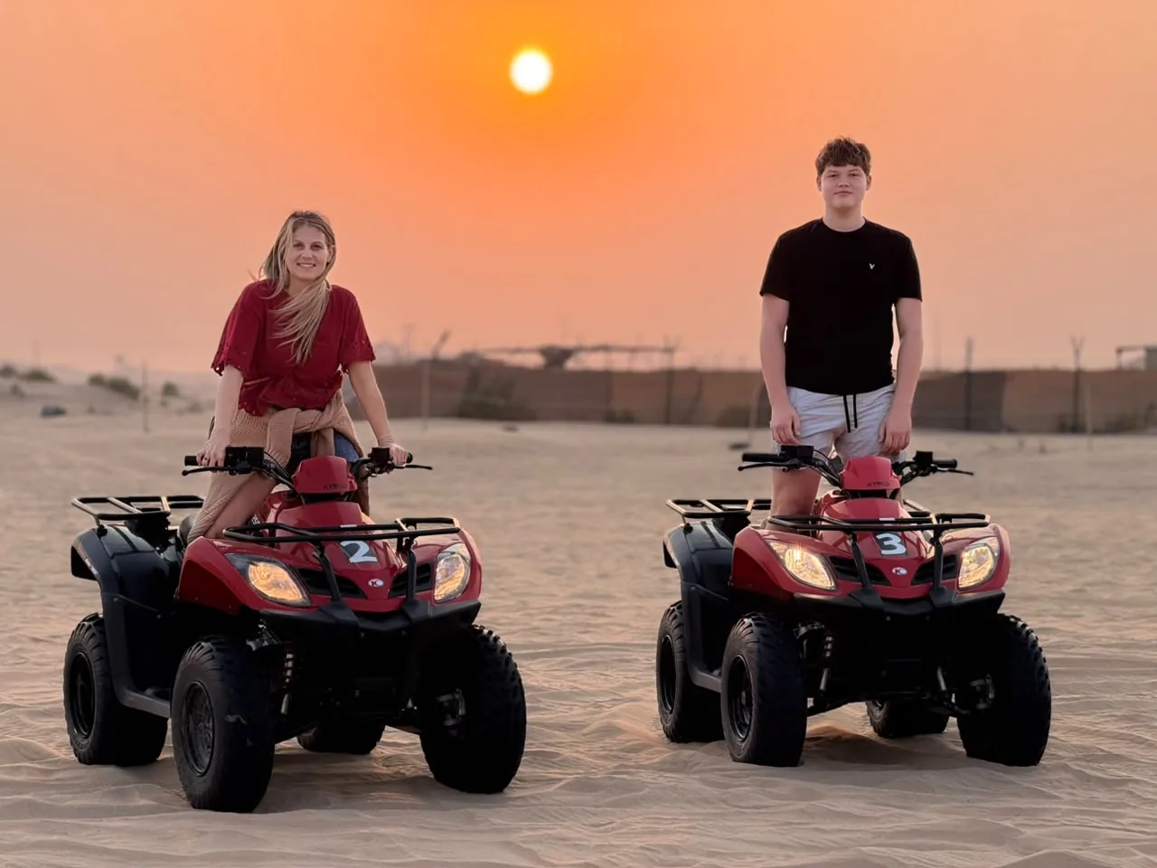 Two red quad bikes ready for a guided sunset ride in the Abu Dhabi desert