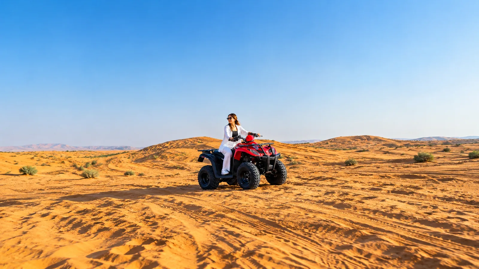 Woman riding a red quad bike across golden Abu Dhabi dunes during a Desert Safari with Quad Bike