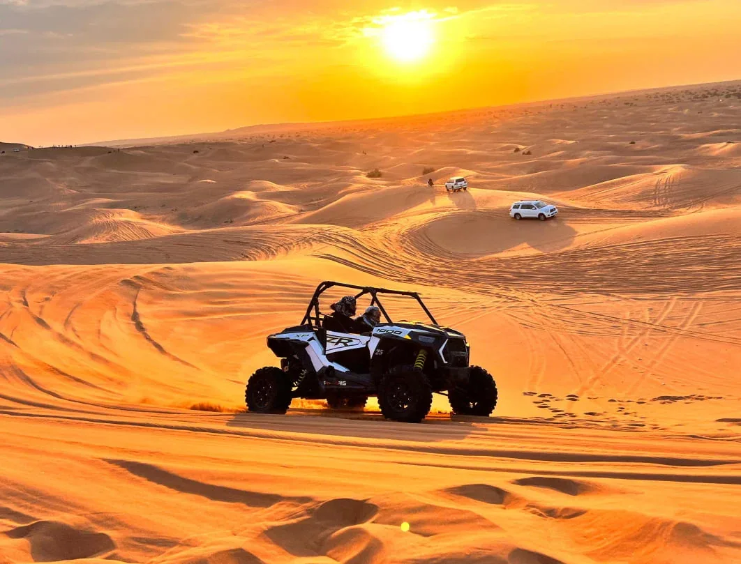 Polaris dune buggy kicking up sand across Abu Dhabi desert dunes on a private dune buggy safari