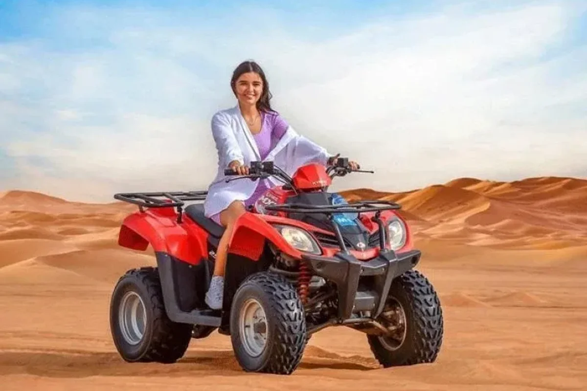 Single seater quad bike kicking up sand on open desert dunes in Abu Dhabi
